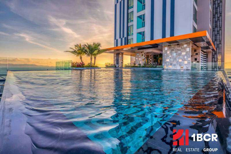 Infinity pool under construction in an apartment building in Pattaya, at sunset with palm trees in the background.