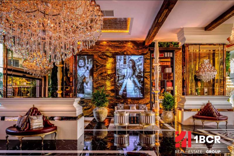 Luxurious interior with a crystal chandelier, golden decor, and artistic photographs on the wall.