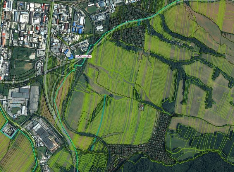 Aerial view of agricultural and forest lands in the Prievidza district with adjacent buildings.