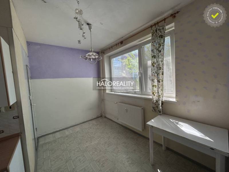 A room in a studio apartment with a purple wall and a white table under the window.