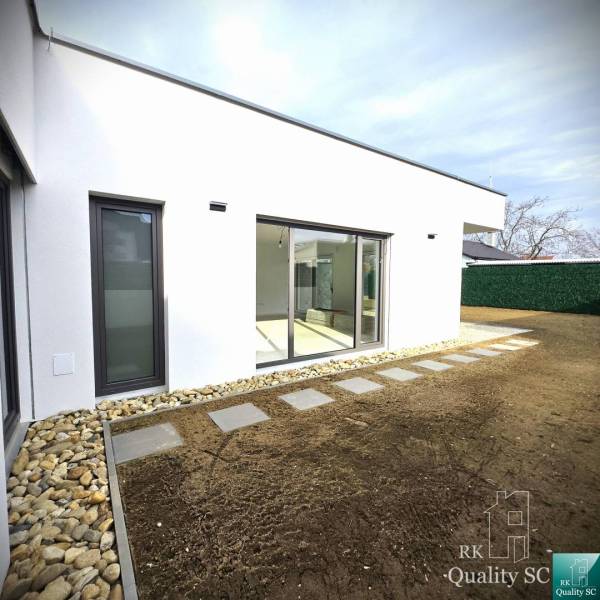 A family house in Turany with a glass-enclosed terrace and a landscaped garden.