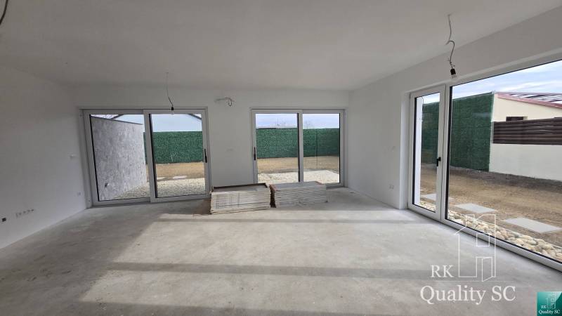 A spacious living room in a family house with large windows, preparing for completion.