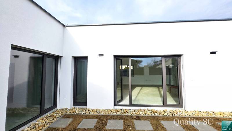 The exterior of a family house in Turany with glass doors and a stone walkway.