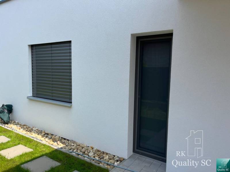 A family house in Turen with a white facade, window, door, and pebbles by the wall.