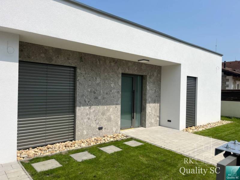 A family house in Turany with a stone facade, windows with shutters, and a well-maintained lawn.