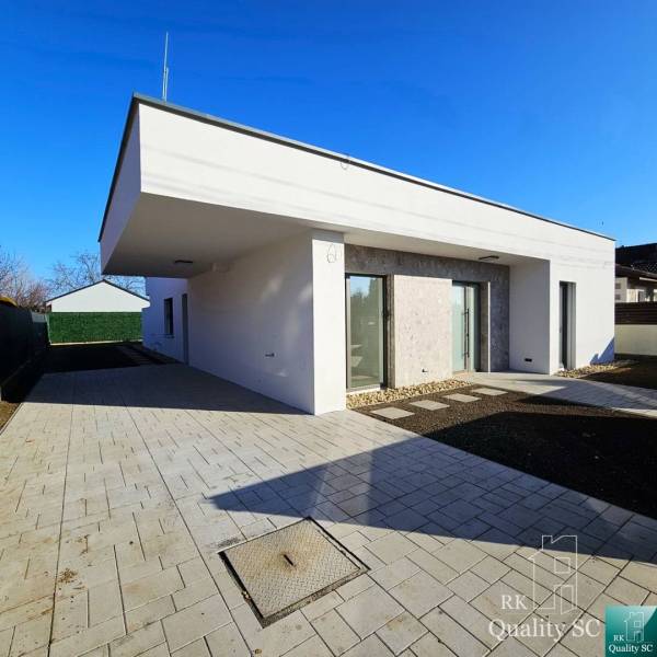 Family house in Turany with a flat roof, paved driveway, and garden shed.