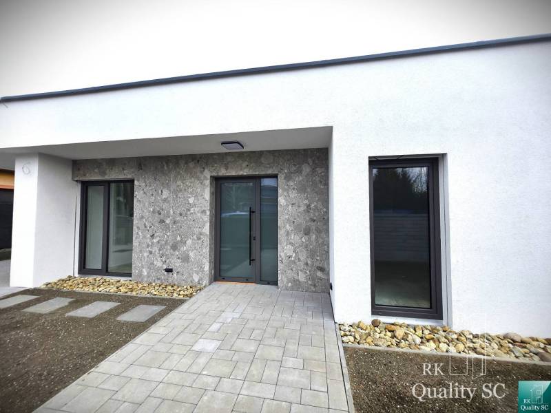 A family house in Tureň with stone cladding, a walkway, and a minimalist design.