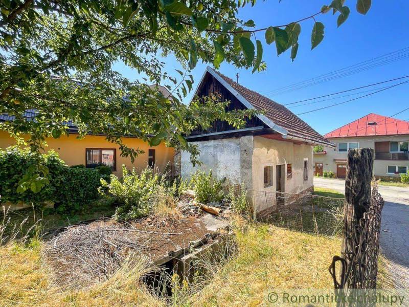 A family house in Banská Bystrica, surrounded by greenery and an older fence.