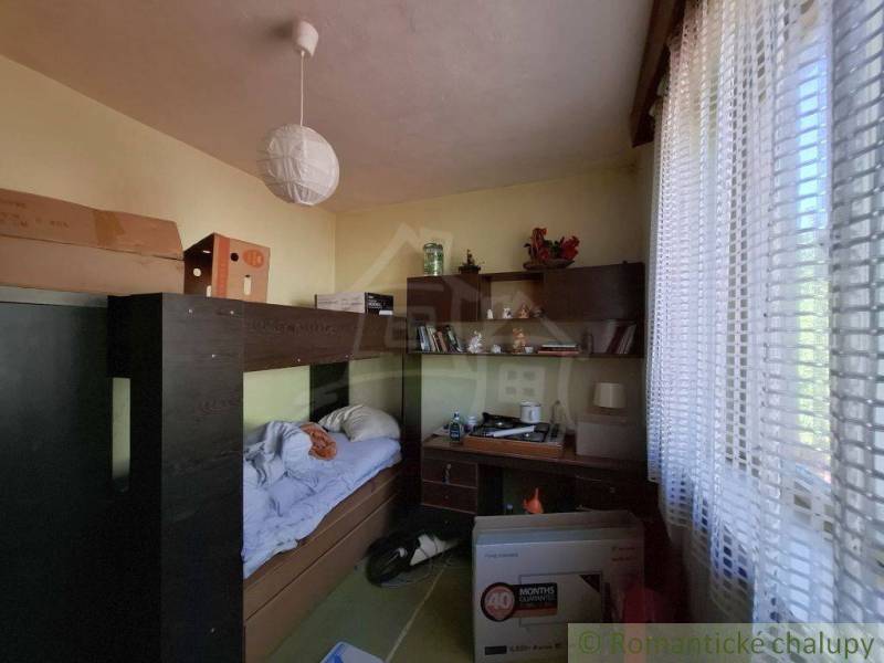 A room in a family house with a bed, table, and shelf.