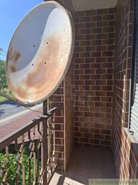 A balcony of a family house in Lovinobaňa, with a metal railing and a satellite dish.