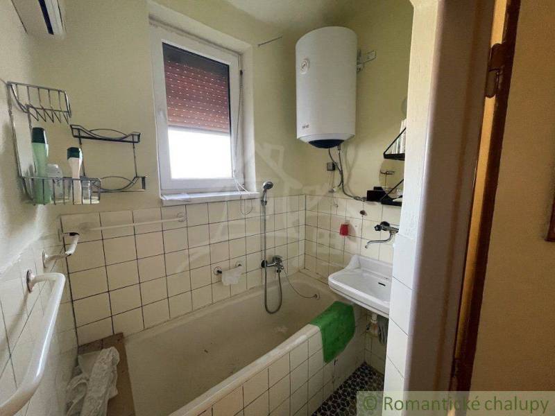 A bathroom in a family house with a shower, a sink, and a water heater.