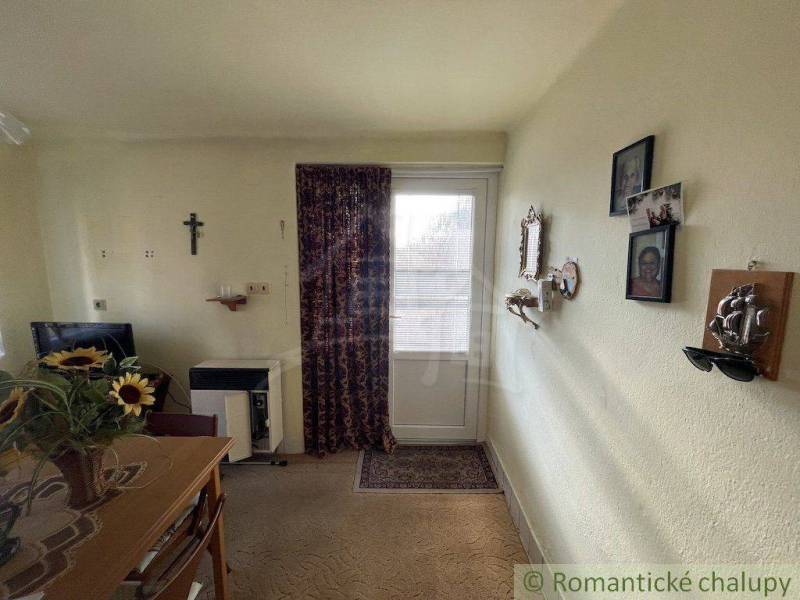Living room in a family house with a cross, photographs, and sunflowers on the table.