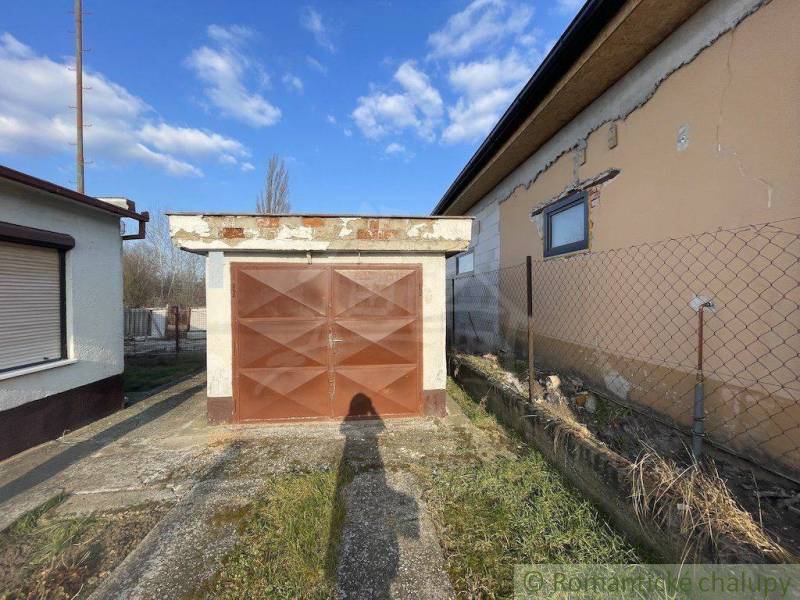 A garage at a family house in Nové Zámky with an older fence and a blue sky.