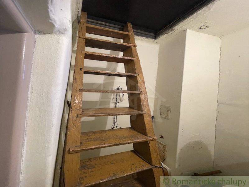 Stairs leading to the attic in a family house, wood and white walls.
