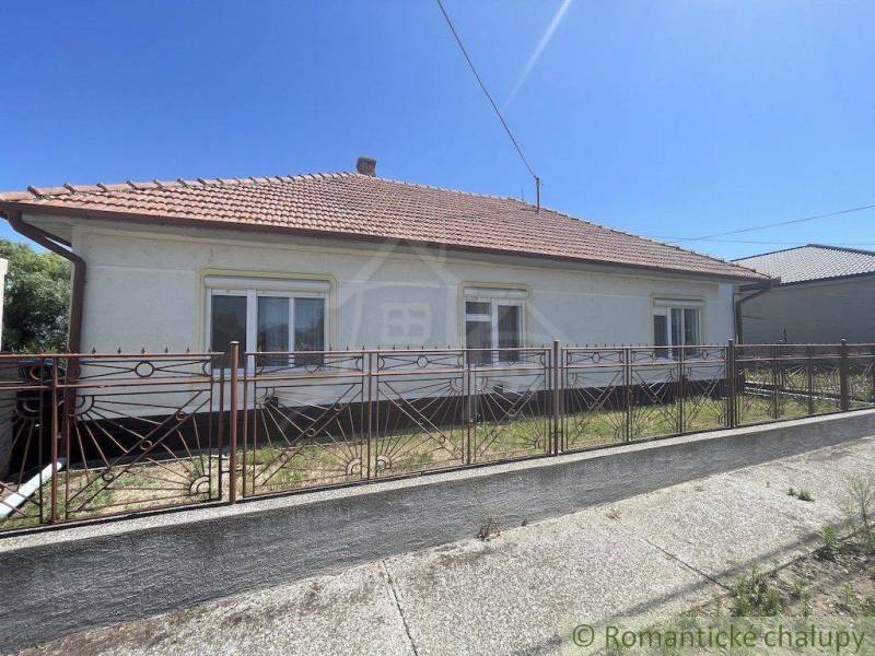 A family house in Nové Zámky with a sloped roof and a wrought iron fence.