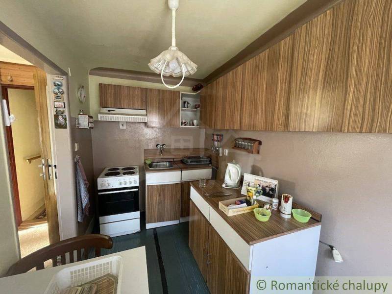 A kitchen in a family house with wooden furniture, a stove, and a table for meal preparation.