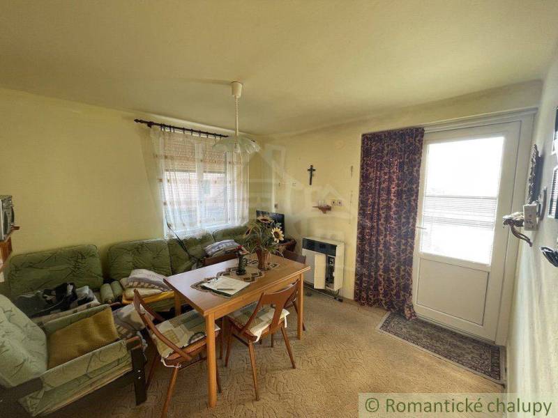Living room in a family house with a sofa, table, chairs, and decorated curtains.