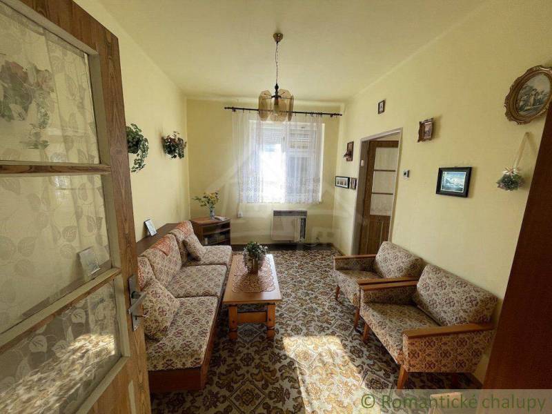 A living room in a family house with floral furniture and wooden elements.