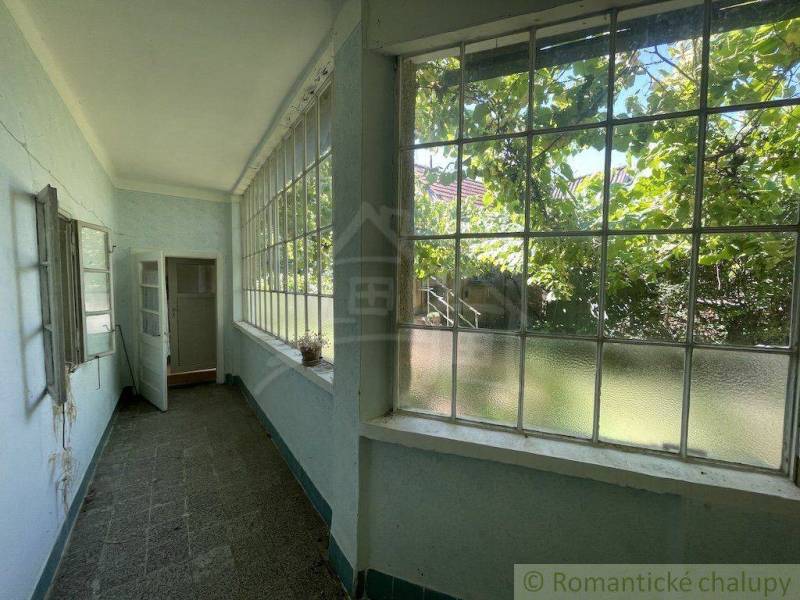 A bright veranda of a family house with large windows and a view of the garden.