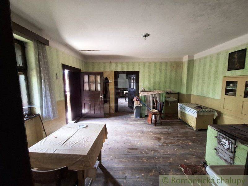 Interior of a family house with wooden flooring, antique furniture, and a simple table.