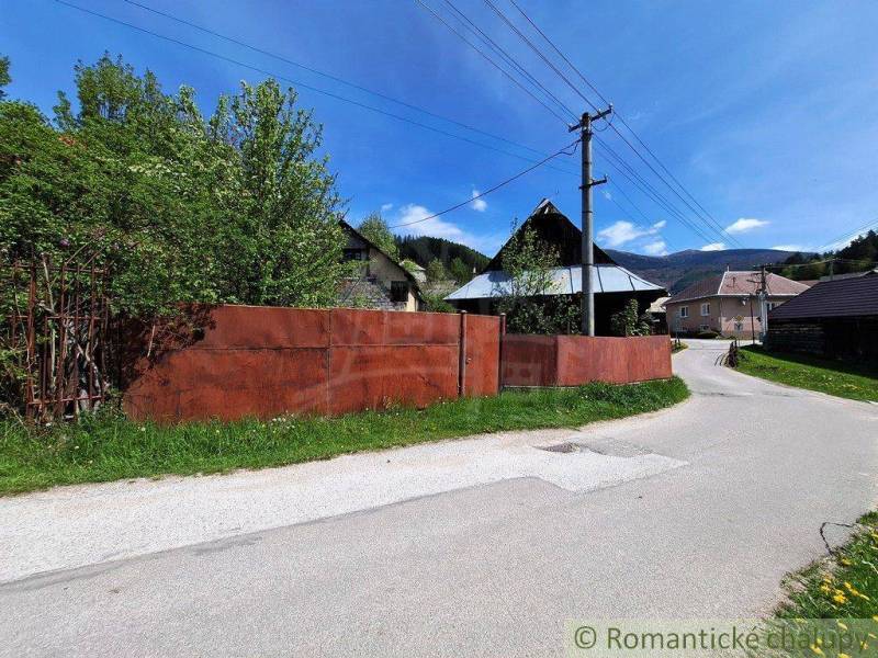 A family house in Pohorelá with a garden, a metal fence, and electric poles by the road.
