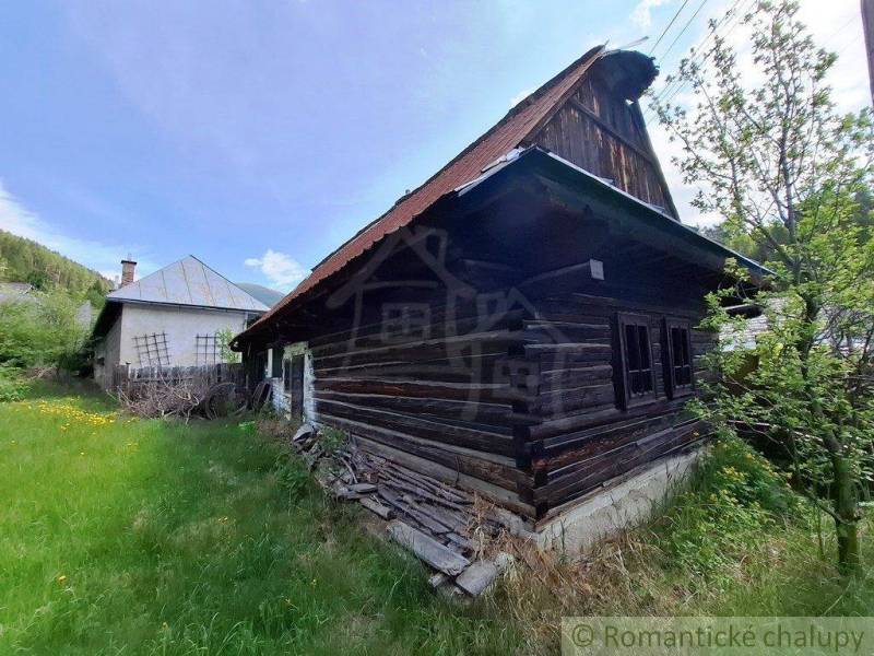 A family house in Pohorelá with an old wooden house and a grassy garden.