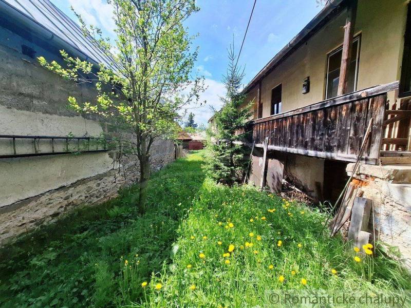 A family house in Pohorelá, a grassy yard with flowers and trees, a wooden veranda.