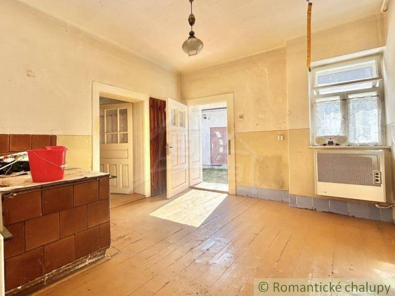 A spacious room with wooden flooring and windows in a family house, light streaming through the doors.