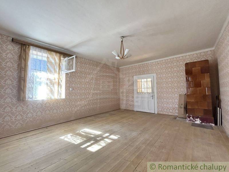 A spacious room in a family house with wooden flooring, wallpaper, and ceramic tiles.