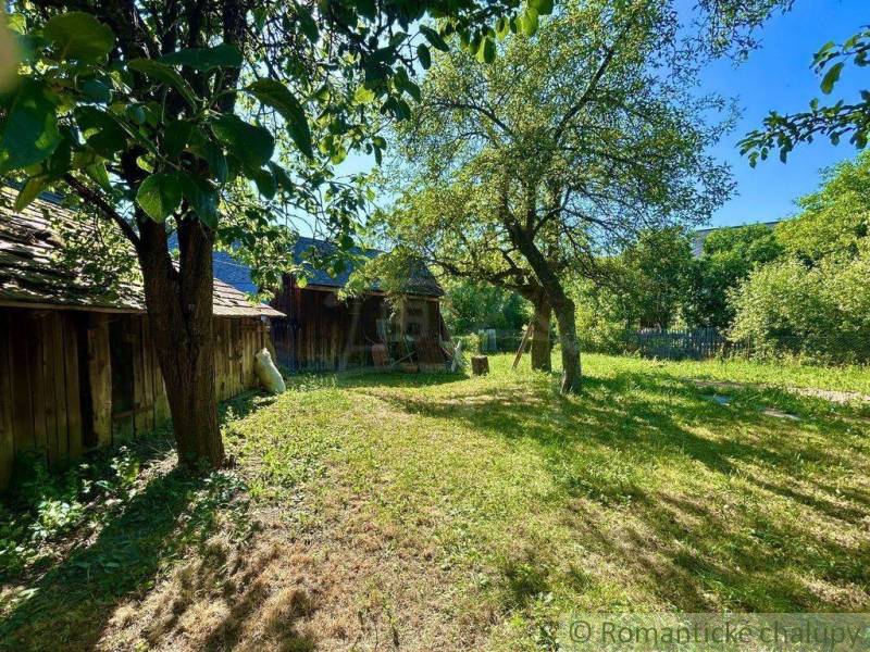 A garden by a family house in Gemerská Poloma, surrounded by fruit trees and a wooden fence.