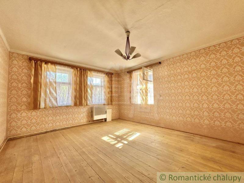 A room in a family house with a wooden floor and wallpaper.