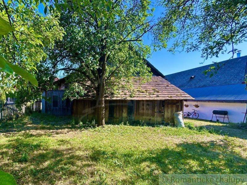 A family house in Gemerská Poloma with a garden, a tree, and a wooden annex.