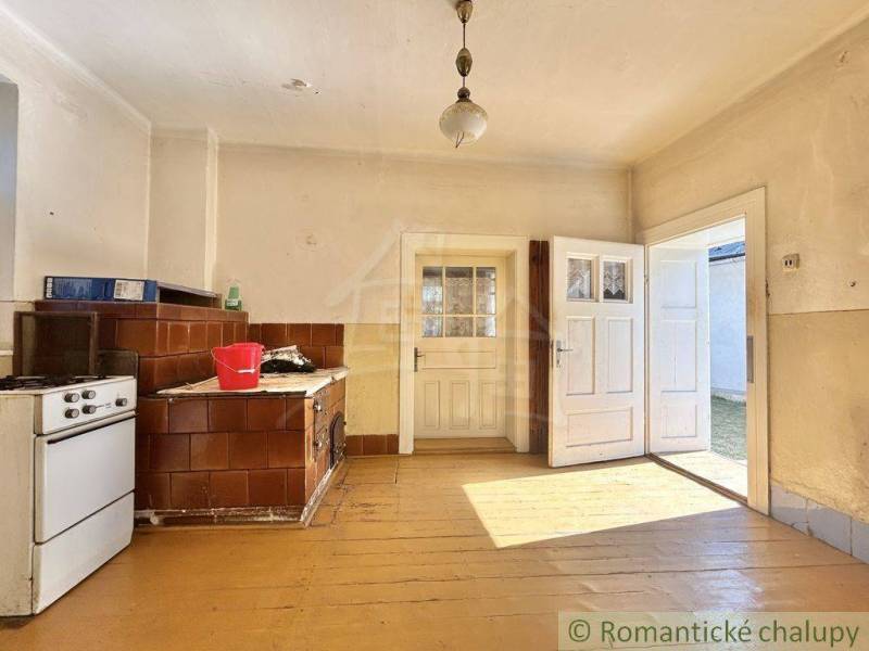 Traditional kitchen in a family house with a tiled stove and wooden plank flooring.