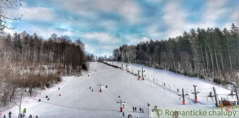 A ski slope surrounded by forests in Stará Myjava with lifts and skiers.