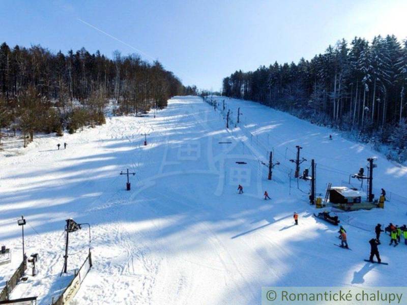 A snowy slope with a ski lift surrounded by forests in Stará Myjava.