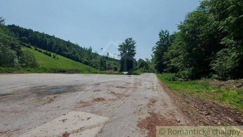 A parking lot surrounded by forests and meadows in Stará Myjava near commercial premises.