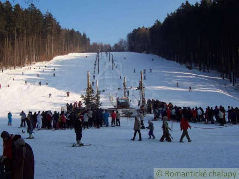 A snowy ski slope with trees, many people, and a lift in Stará Myjava.
