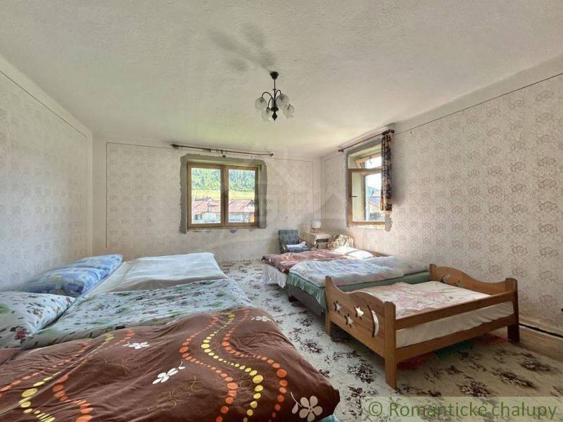 A bedroom in a family house with multiple beds, wallpapers, and windows with a view.