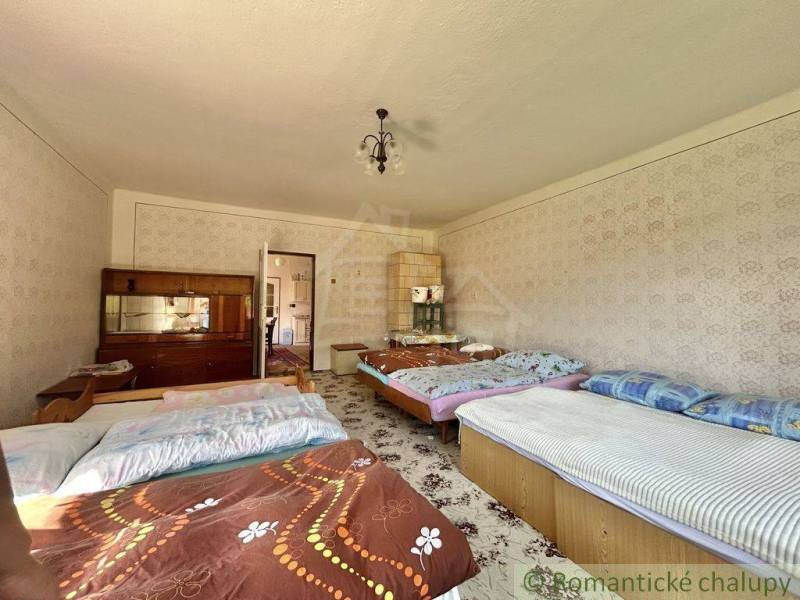 A bedroom in a family house with five beds, a wardrobe, and decorative wallpaper.