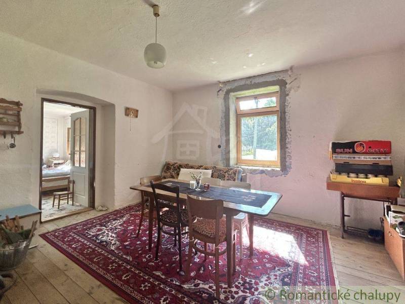 Dining room in a family house with a wooden table and a carpet, rustic furnishings.