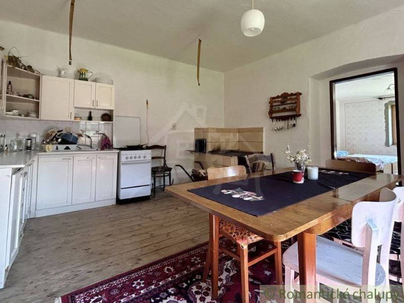 A kitchen in a family house with a wooden table, kitchen unit, and a tiled stove.