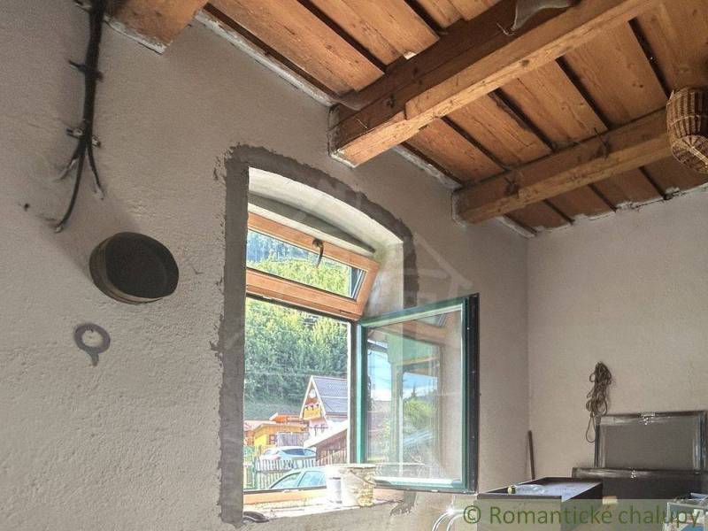 Wooden ceiling and open window with a view in the interior of a family house.