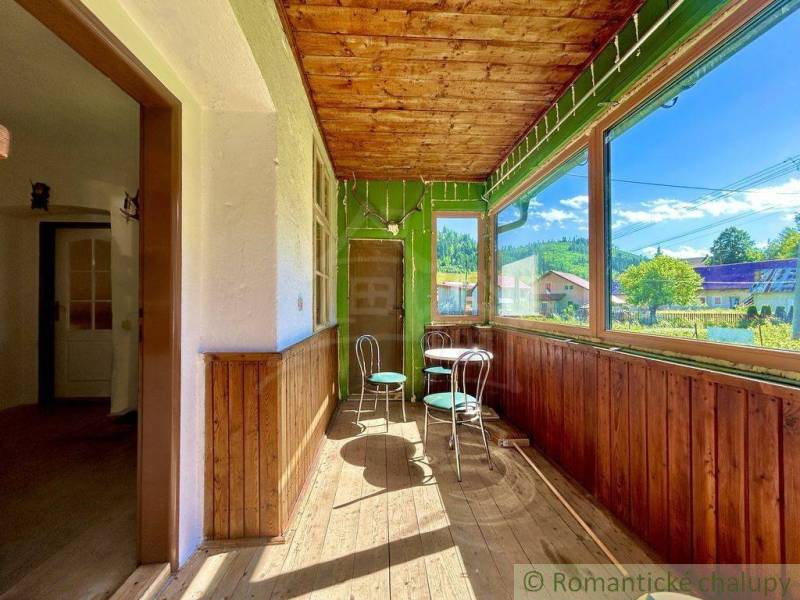 A glazed veranda in a family house with wooden chairs and a view of the garden.