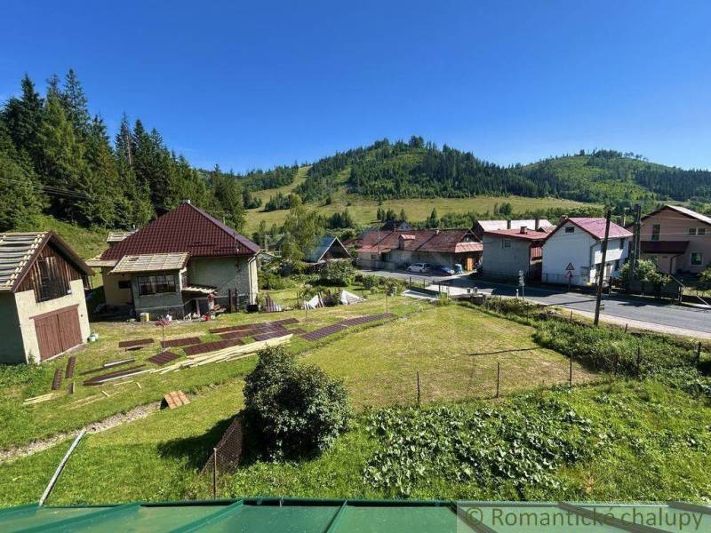 A family house in Spišská Nová Ves surrounded by green hills and a meadow plot.