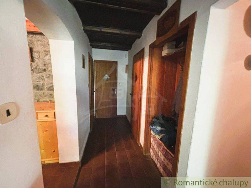 A hallway in a family house with wooden paneling and a stone wall.