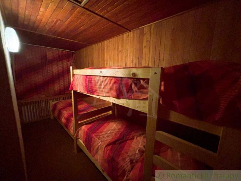 Bunk beds with red bedding in a wooden room of a family house.