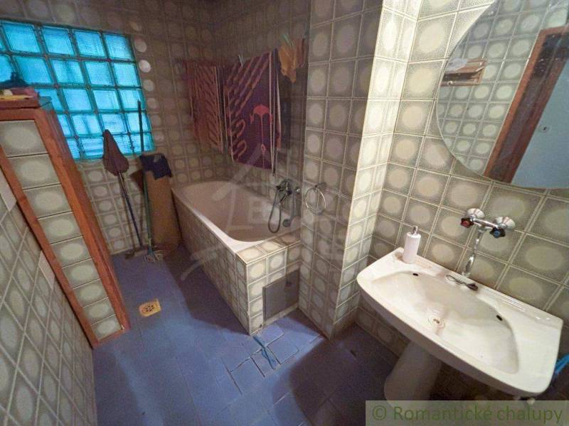 A bathroom with a dark bathtub, sink, and colorful stained glass window in a family house.