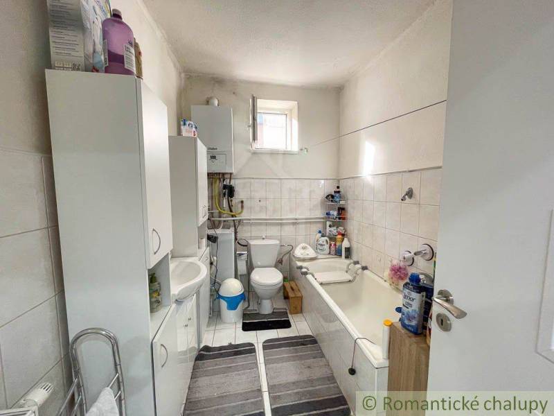 A bathroom in a family house with sanitary ware, cabinets, and a bathtub.