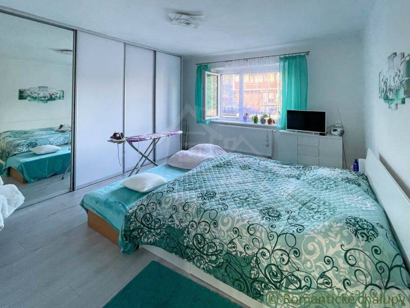 Bedroom in a family house with a large bed and green curtains, bright interior.
