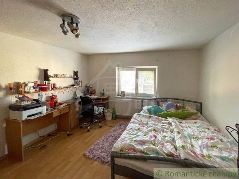 A bedroom in a family house with a bed, a desk, and simple lighting.
